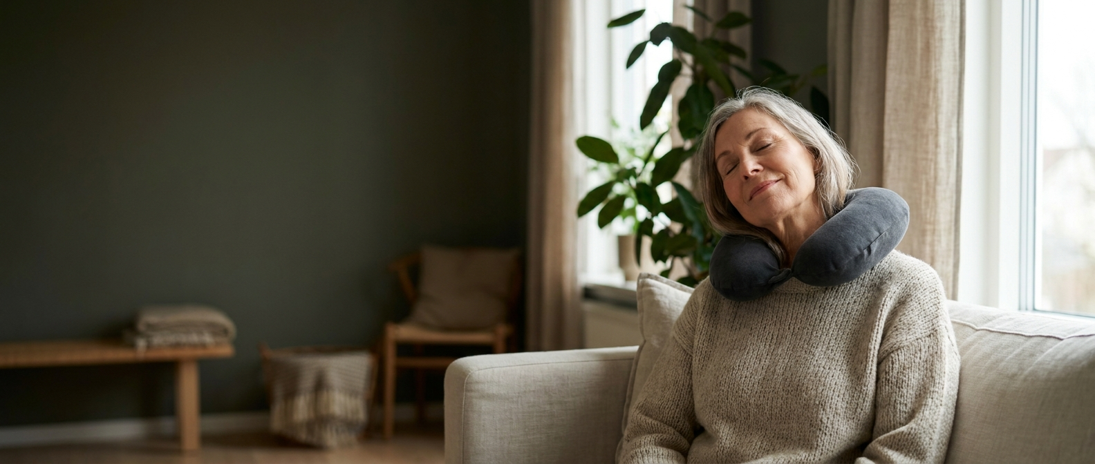 A woman in her sixties resting on her sofa at home with the Salureva neck cushion around her shoulders